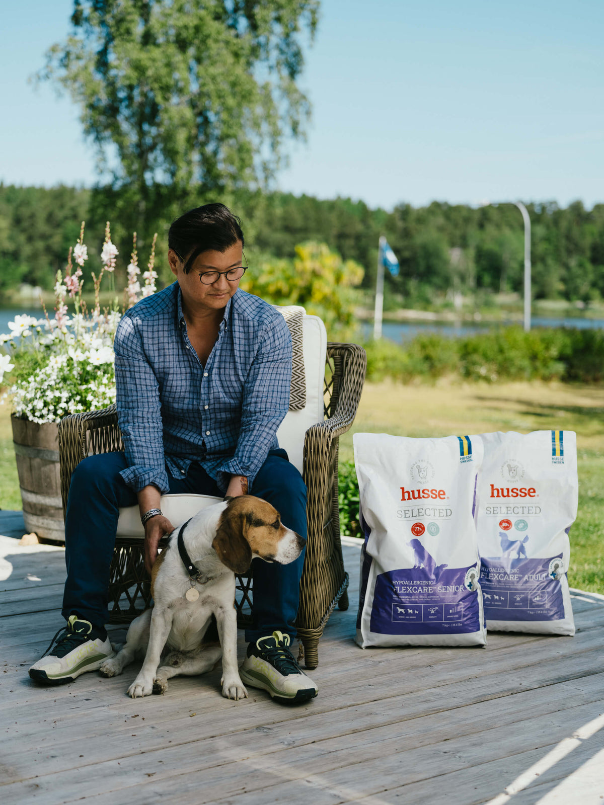 Dog owner on a lakeside deck in Sweden with his beagle and two bags of Husse Selected dry dog food