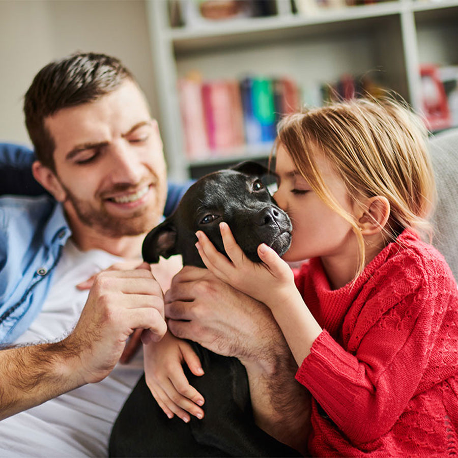Father and daughter holding their new black puppy at home
