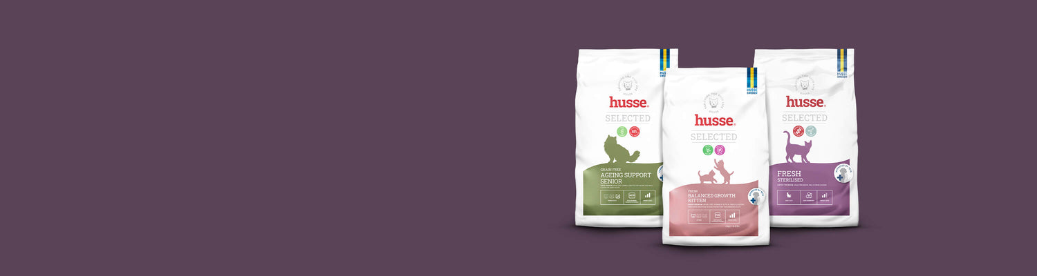 Three bags from the Husse Selected cat food range on a plum background