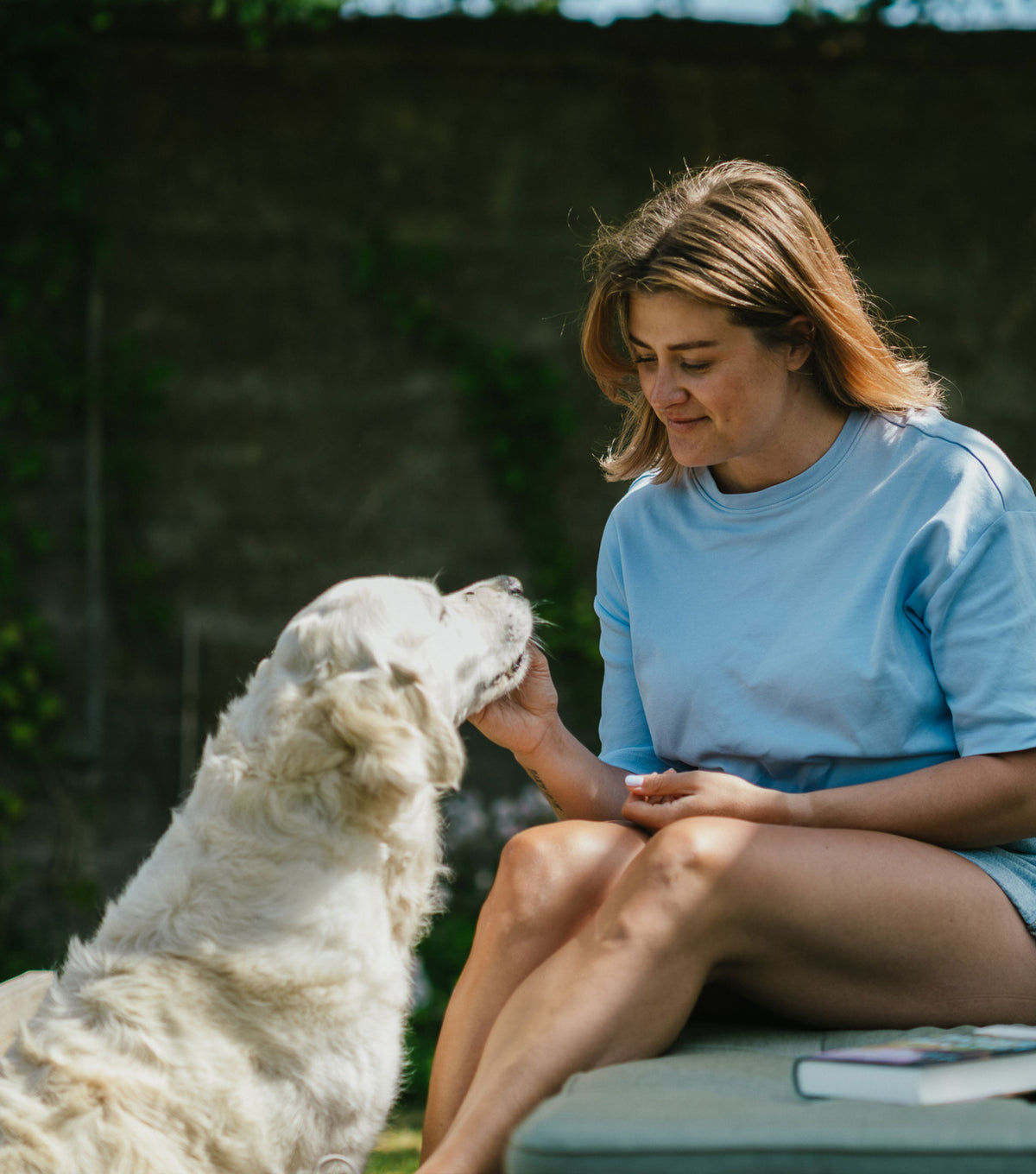 Woman sitting on the floor at home with her golden retriever resting beside her