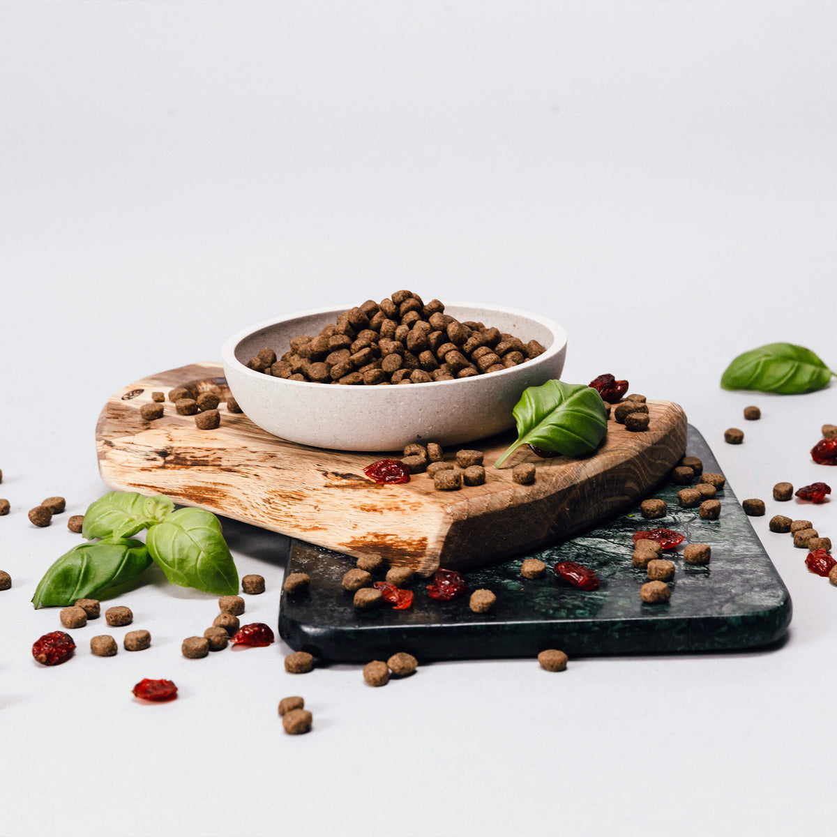 Bowl of Husse dry pet food on a wooden board with fresh basil and scattered kibble
