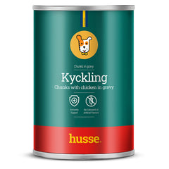 Alimento húmido para cão Husse Kyckling com pedaços de frango em molho numa lata verde e vermelha.