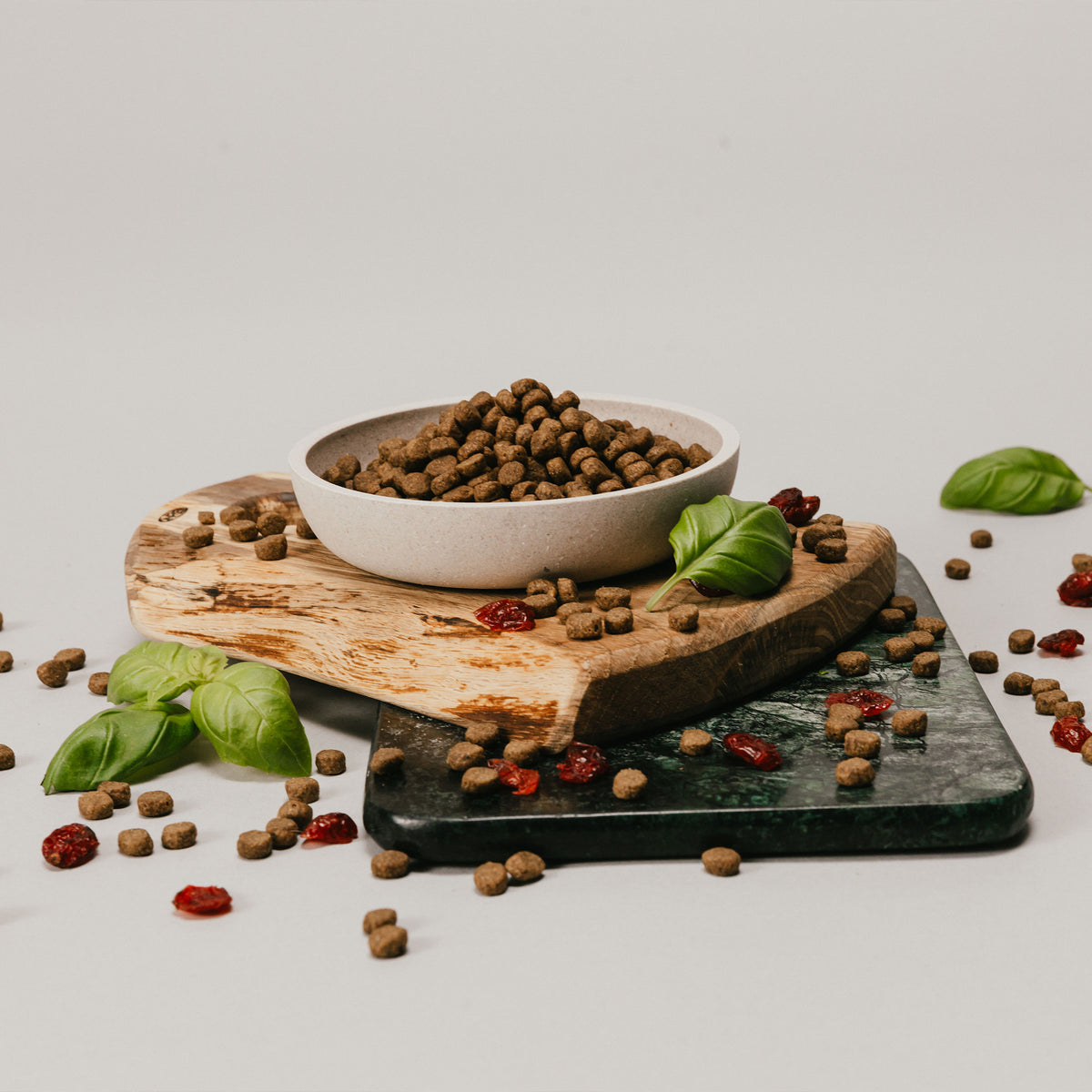 Bowl of Husse dry pet food on a wooden board with fresh basil and scattered kibble